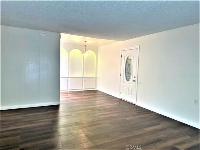 interior space featuring a chandelier, baseboards, a textured ceiling, and dark wood-type flooring