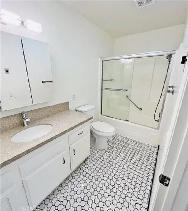 bathroom featuring shower / bath combination with glass door, tile patterned floors, visible vents, toilet, and vanity
