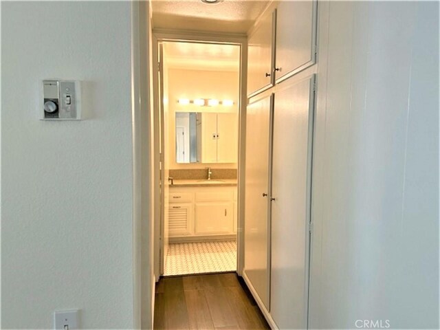 corridor featuring dark wood-style floors and a sink