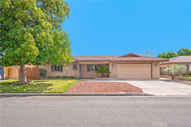 ranch-style house featuring a tile roof, concrete driveway, fence, an attached garage, and a front yard