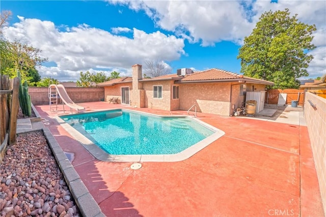 view of pool featuring a water slide, a fenced in pool, a fenced backyard, central AC, and a patio area