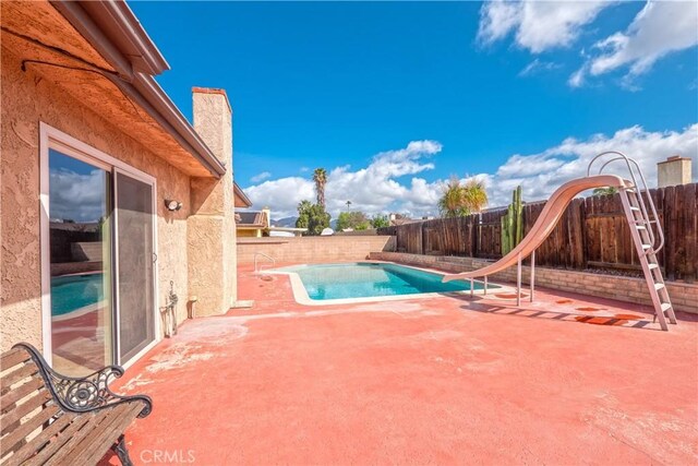 view of pool featuring a fenced in pool, a patio area, a water slide, and a fenced backyard
