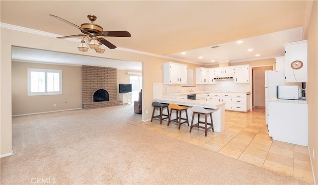 kitchen with a peninsula, crown molding, and white microwave