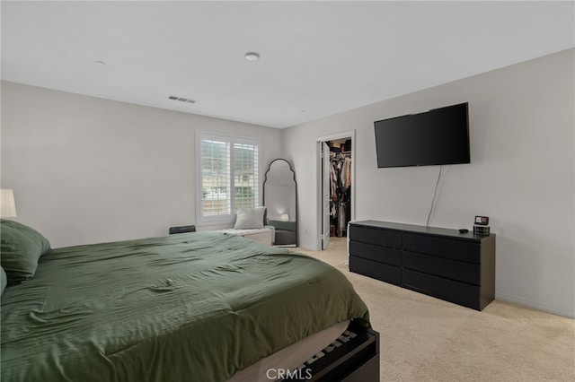 bedroom with a walk in closet, a closet, visible vents, and light carpet