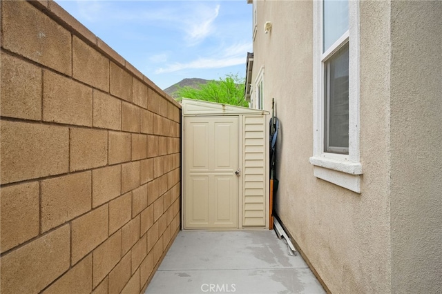 view of home's exterior featuring fence, a shed, an outbuilding, and stucco siding