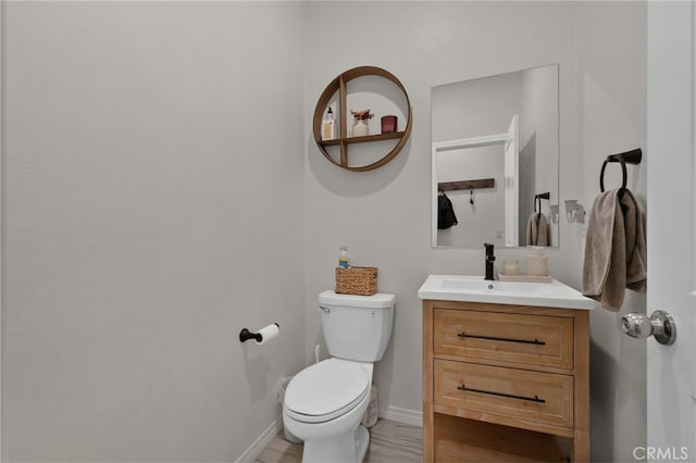 bathroom with baseboards, vanity, and toilet