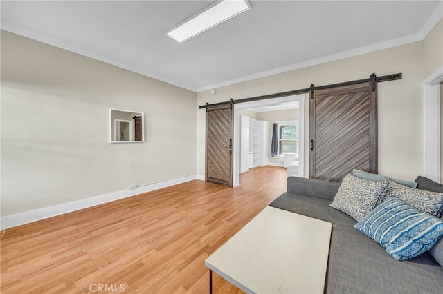 living area featuring a barn door, baseboards, ornamental molding, and light wood-style flooring
