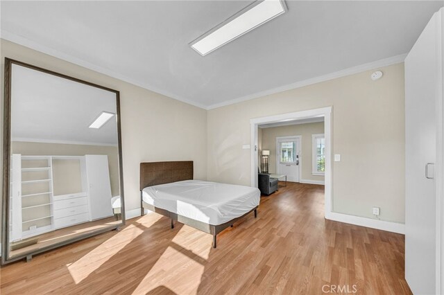 bedroom featuring light wood-style floors, crown molding, and baseboards