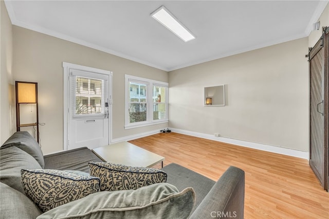 living room with a barn door, baseboards, ornamental molding, and light wood finished floors