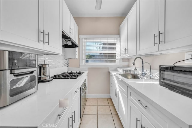 kitchen with light countertops, under cabinet range hood, a sink, and light tile patterned flooring