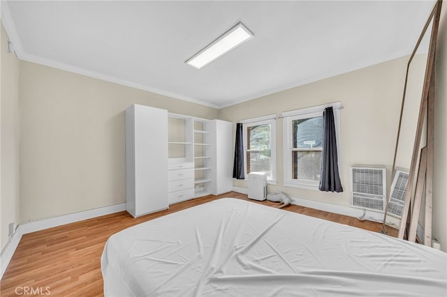 bedroom featuring light wood-style floors, crown molding, and baseboards