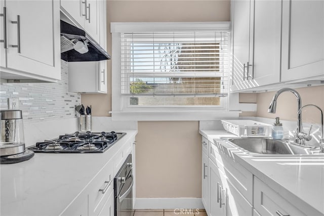 kitchen featuring a sink, gas cooktop, oven, white cabinetry, and under cabinet range hood