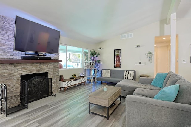 living area featuring high vaulted ceiling, wood finished floors, visible vents, and a fireplace