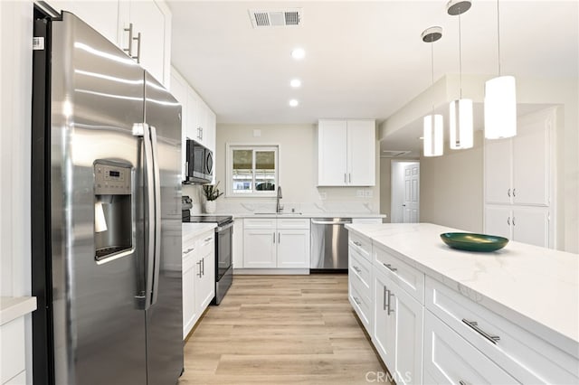 kitchen featuring light stone counters, a sink, stainless steel appliances, white cabinetry, and visible vents