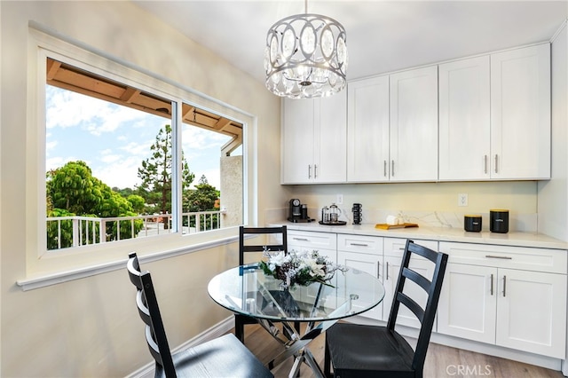 dining area featuring a chandelier, light wood finished floors, and baseboards