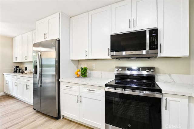 kitchen with light wood-style flooring, appliances with stainless steel finishes, and white cabinetry