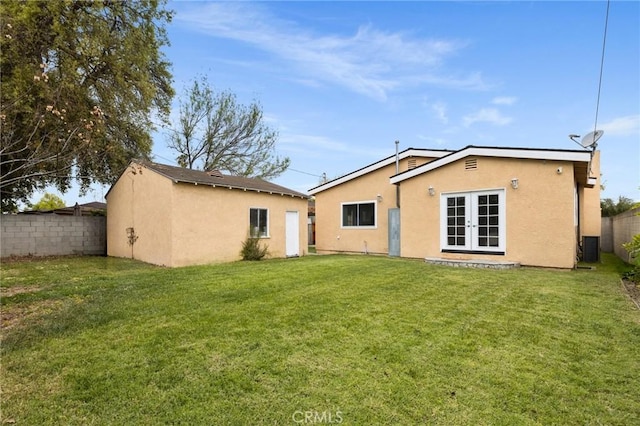 rear view of house featuring stucco siding, a yard, fence private yard, and french doors