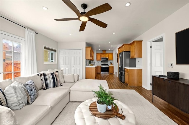 living room featuring a ceiling fan, baseboards, recessed lighting, and light wood-style floors