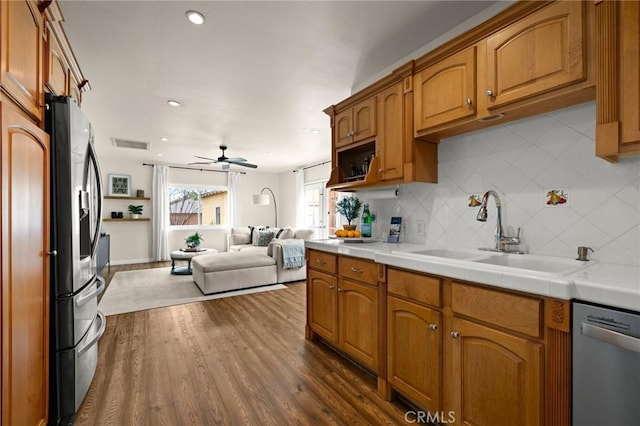 kitchen with stainless steel appliances, a sink, tasteful backsplash, open floor plan, and visible vents