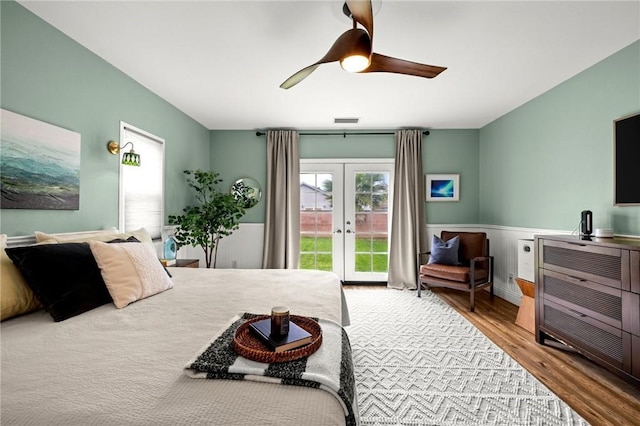 bedroom with wood finished floors, visible vents, access to exterior, french doors, and wainscoting