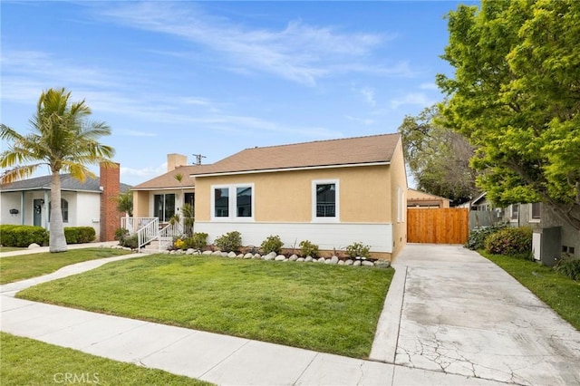 view of front of property with a front lawn, driveway, a chimney, stucco siding, and fence