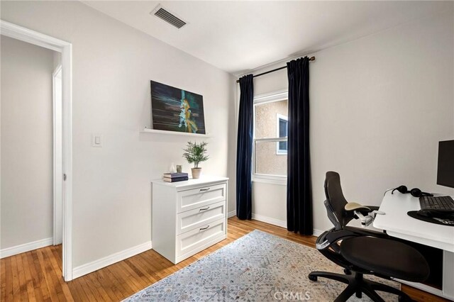 office area with visible vents, light wood finished floors, and baseboards