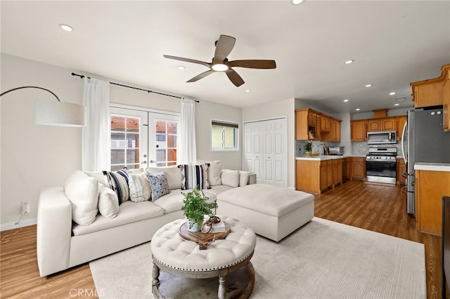 living room with recessed lighting, light wood-type flooring, ceiling fan, and french doors
