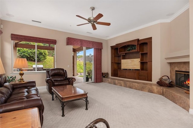 carpeted living room with a premium fireplace, visible vents, ornamental molding, and ceiling fan