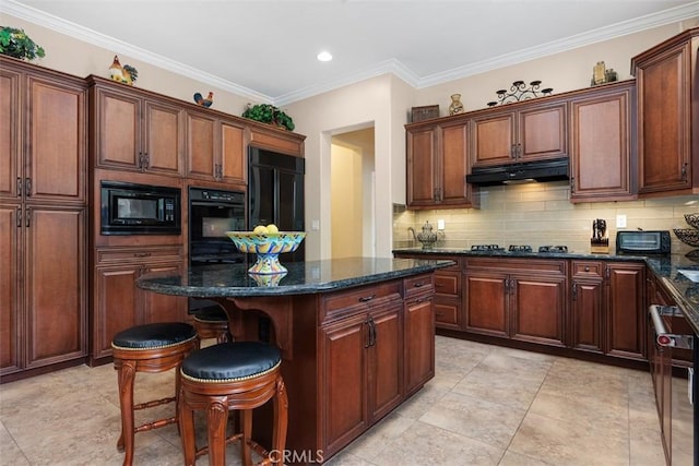 kitchen with decorative backsplash, a breakfast bar, under cabinet range hood, a kitchen island, and black appliances