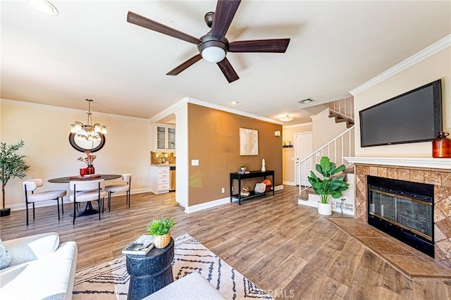 living room with ornamental molding, stairs, visible vents, and wood finished floors