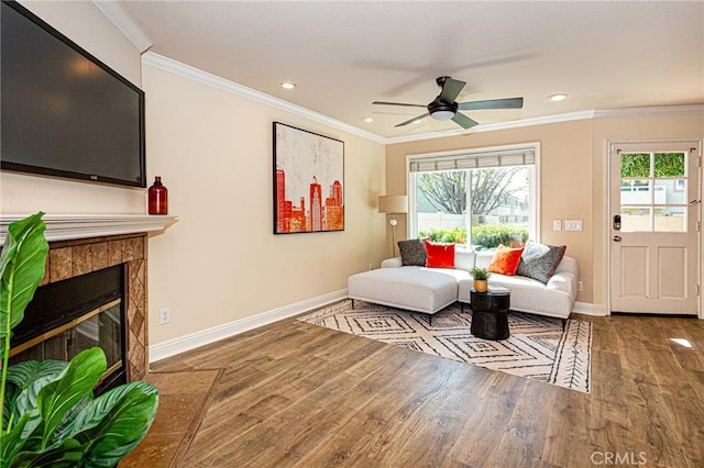 living room with baseboards, ornamental molding, a ceiling fan, and wood finished floors