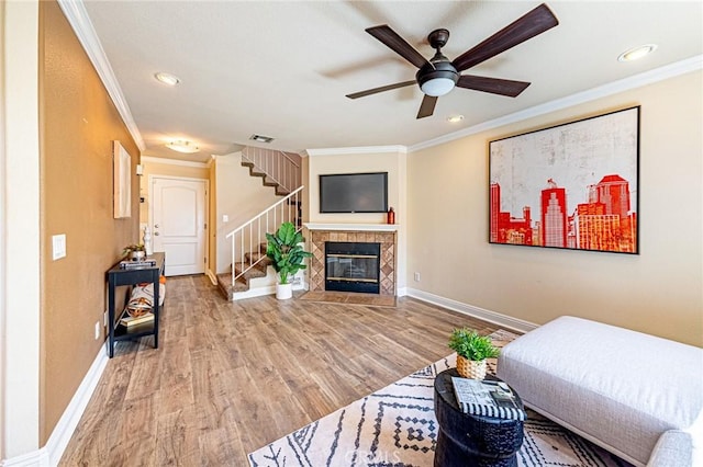 living room featuring stairway, ceiling fan, baseboards, light wood-type flooring, and crown molding