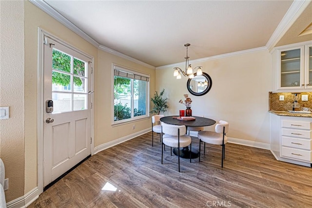 dining area with baseboards, wood finished floors, a notable chandelier, and ornamental molding