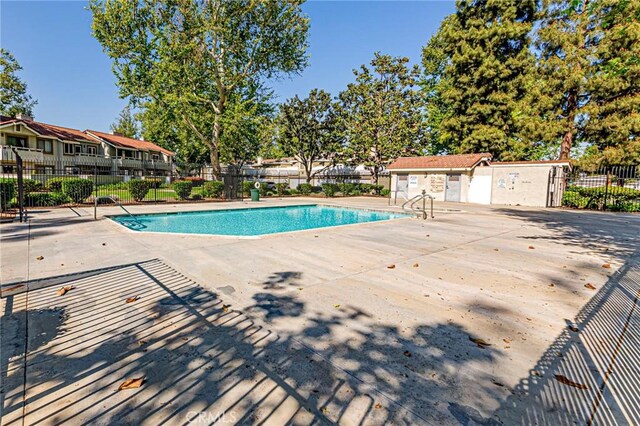 community pool with fence and a patio area