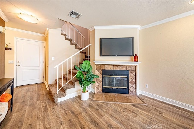 living area featuring crown molding, visible vents, stairway, and wood finished floors