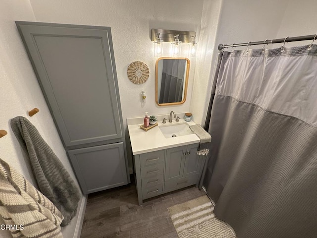 full bathroom featuring a textured wall, wood finished floors, vanity, and a shower with shower curtain