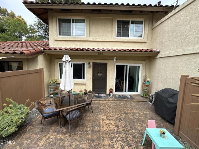 rear view of house with fence, a patio area, and stucco siding