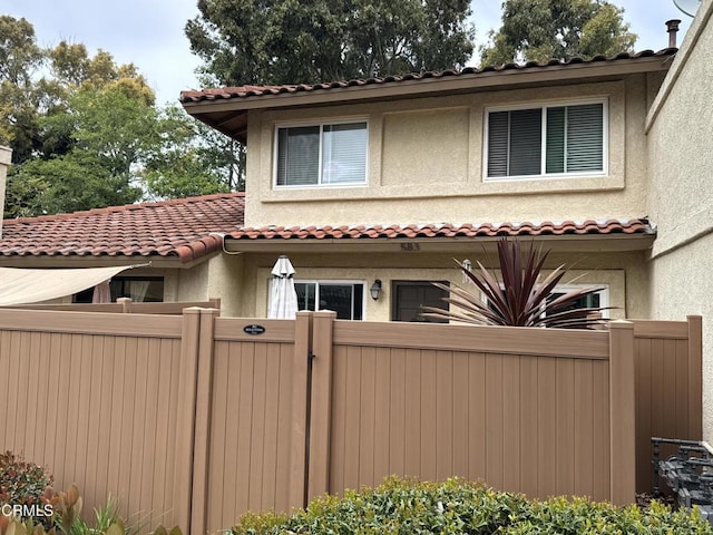 view of front of home featuring fence, a tiled roof, a gate, and stucco siding