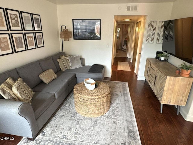 living room with dark wood finished floors, baseboards, and visible vents