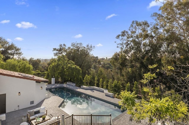 pool with a patio area and a forest view