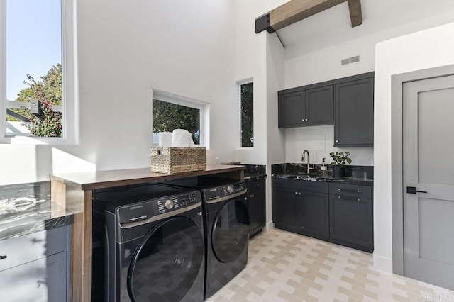 washroom with a towering ceiling, visible vents, independent washer and dryer, and a sink