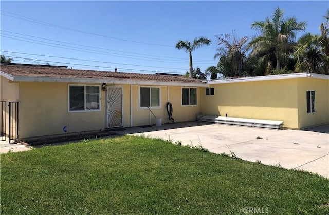 rear view of property featuring stucco siding, a yard, and a patio area