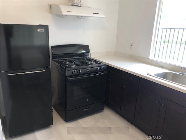 kitchen featuring range hood, light countertops, a sink, black appliances, and dark cabinetry
