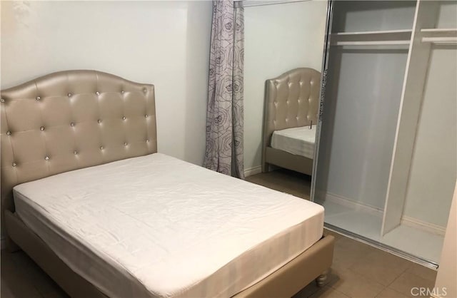 bedroom with tile patterned floors and a closet