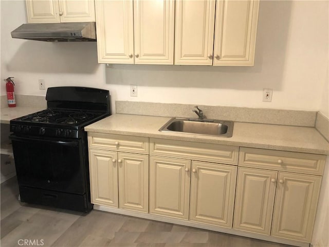 kitchen with black range with gas stovetop, light countertops, white cabinetry, under cabinet range hood, and a sink