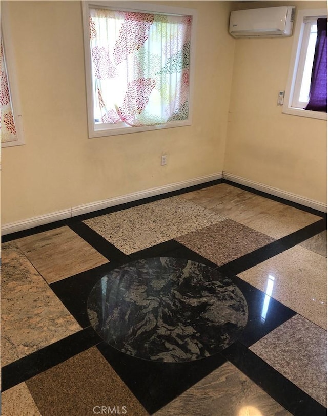 unfurnished room with baseboards, an AC wall unit, and a wealth of natural light
