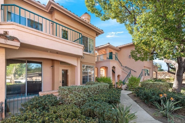 18614 Caminito Cantilena Unit 324, San Diego, CA 92128 - view of exterior entry with stucco siding, a chimney, and a balcony