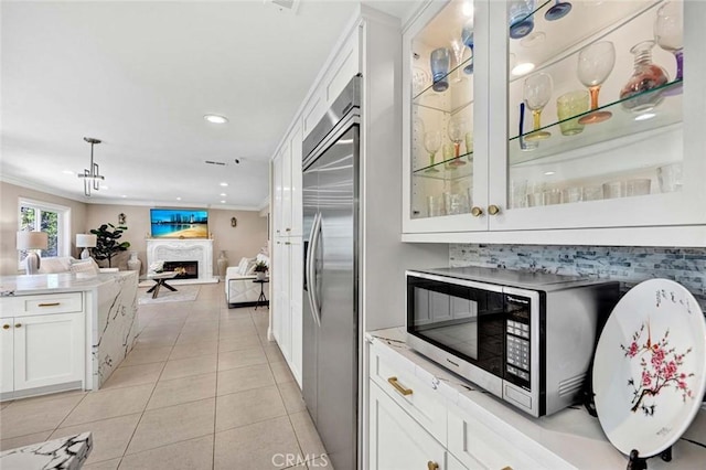 bar featuring built in refrigerator, a warm lit fireplace, crown molding, light tile patterned flooring, and recessed lighting