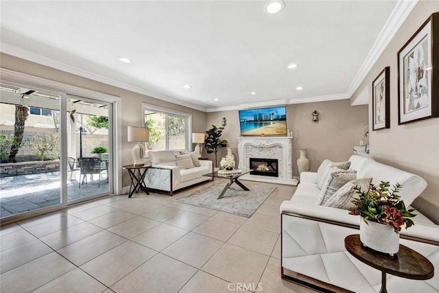living room featuring light tile patterned floors, a glass covered fireplace, recessed lighting, and ornamental molding