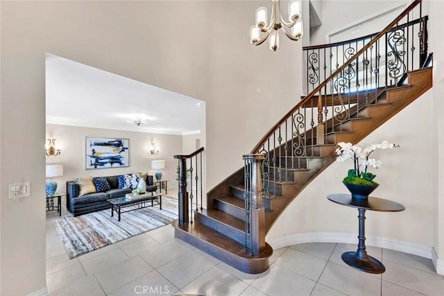stairway with a chandelier, a towering ceiling, baseboards, tile patterned floors, and ornamental molding